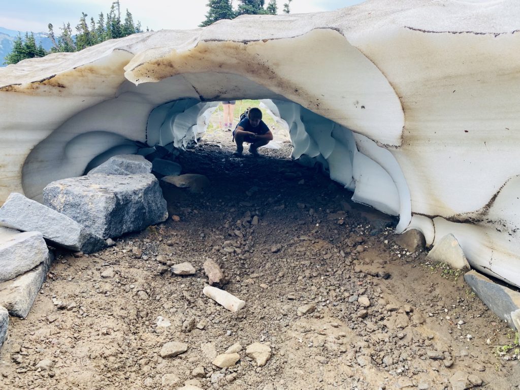 Kids climbing through a snow tunnel created by melting snow