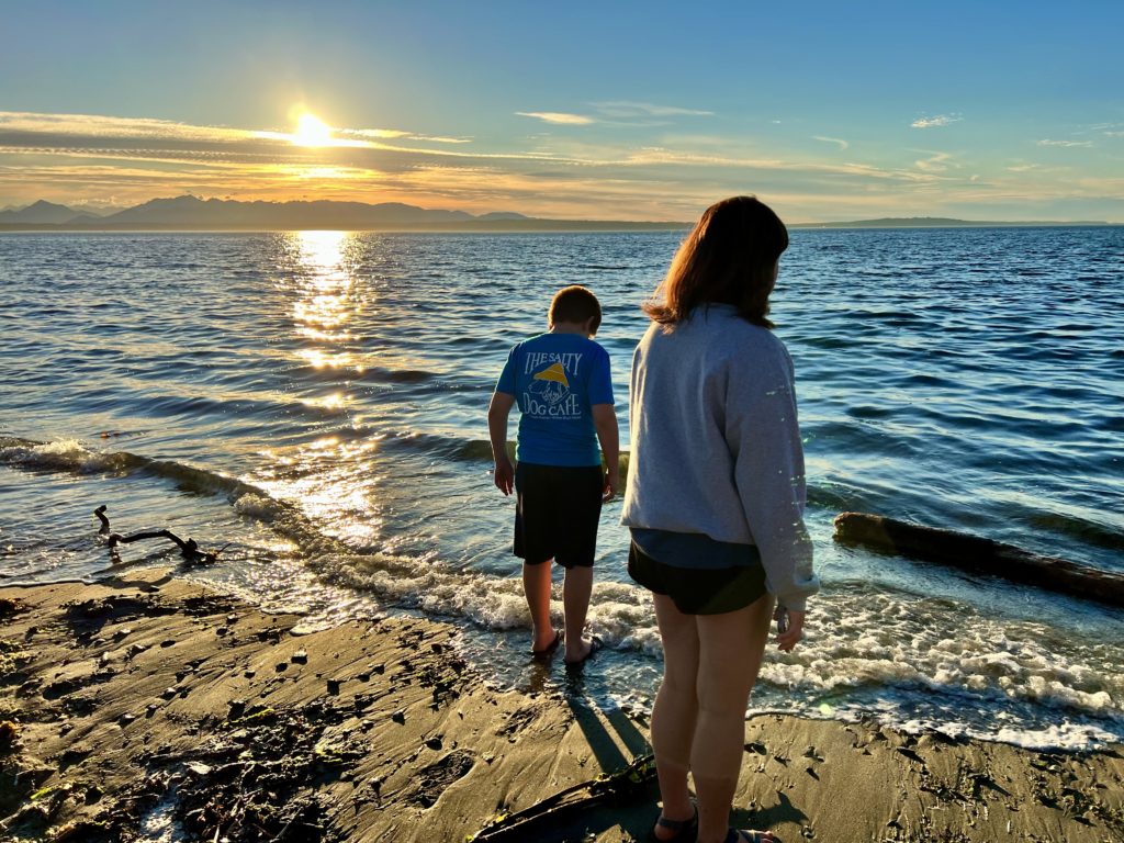 Kids getting feet into Pacific water at Carkeek Park Beach at sunset
