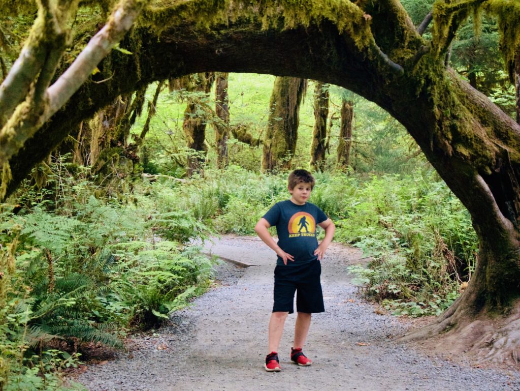 My son posing under a natural moss covered arching tree