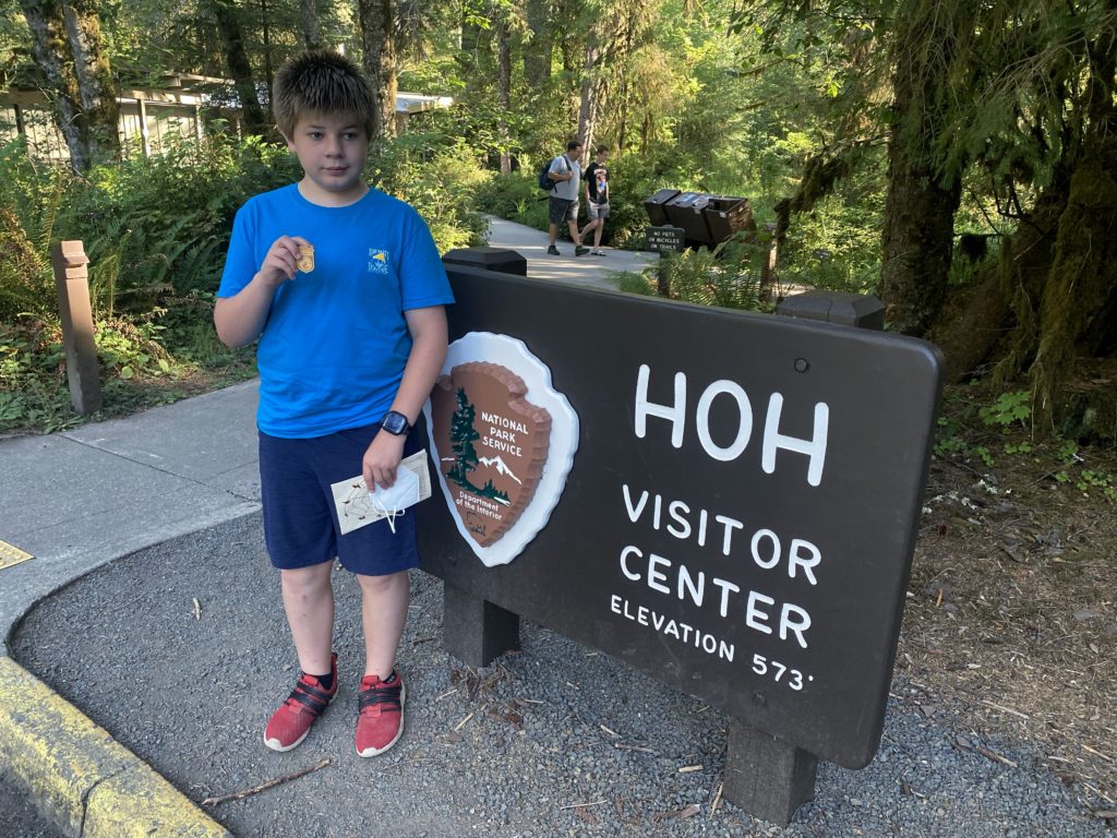 My son holding up his National Parks Junior Ranger Badge in Olympic National Park