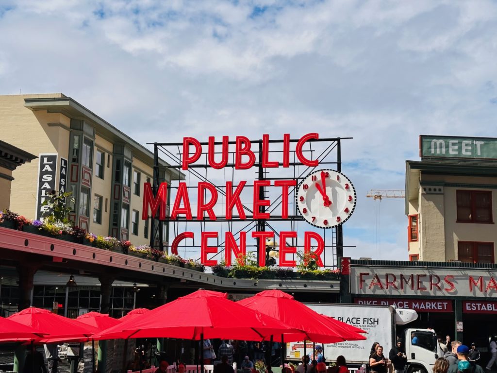 The famous Pike Place sign above the main entry that reads, Public Market Center with the clock display 10:59am.