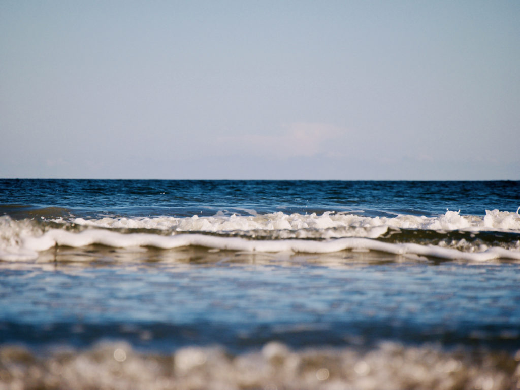 Blue sky, blue Atlantic water of a small wave rolling towards the beach on Hilton Head Island, South Carolina
