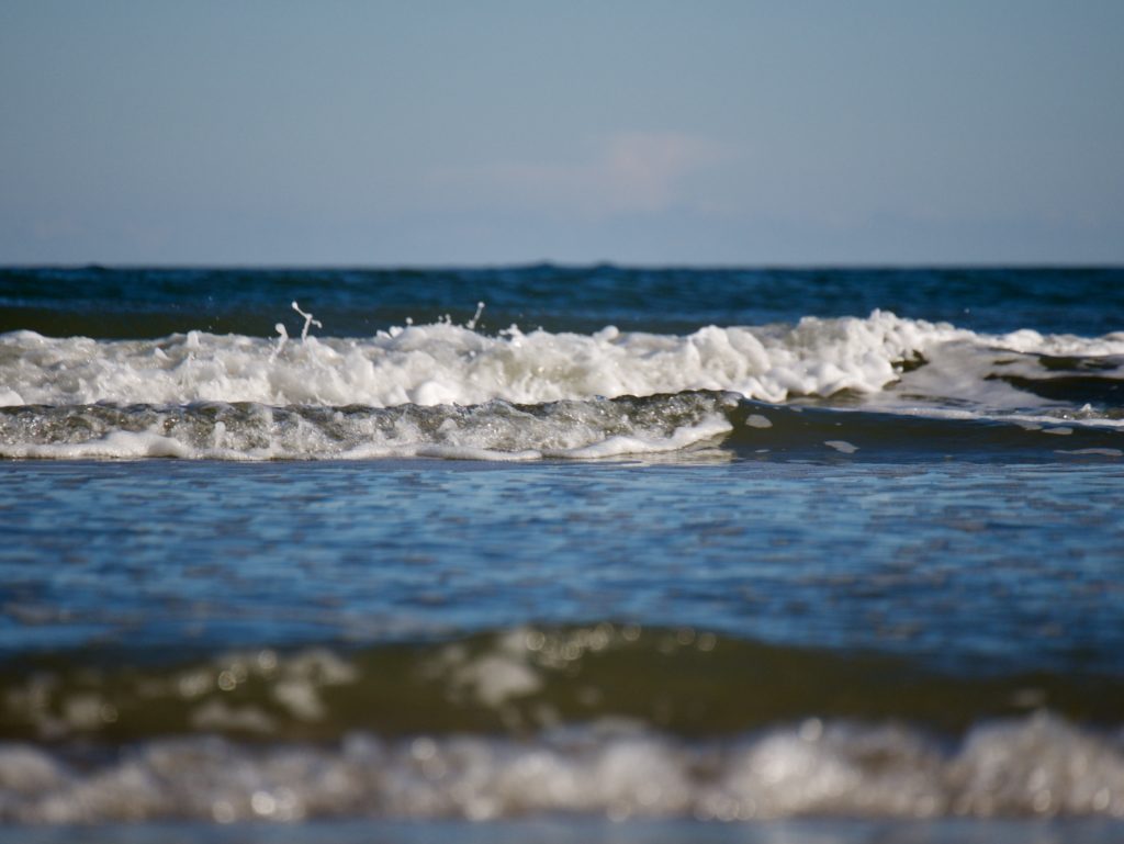 Blue sky, blue Atlantic water of a small foamy wave rolling towards the beach on Hilton Head Island, South Carolina